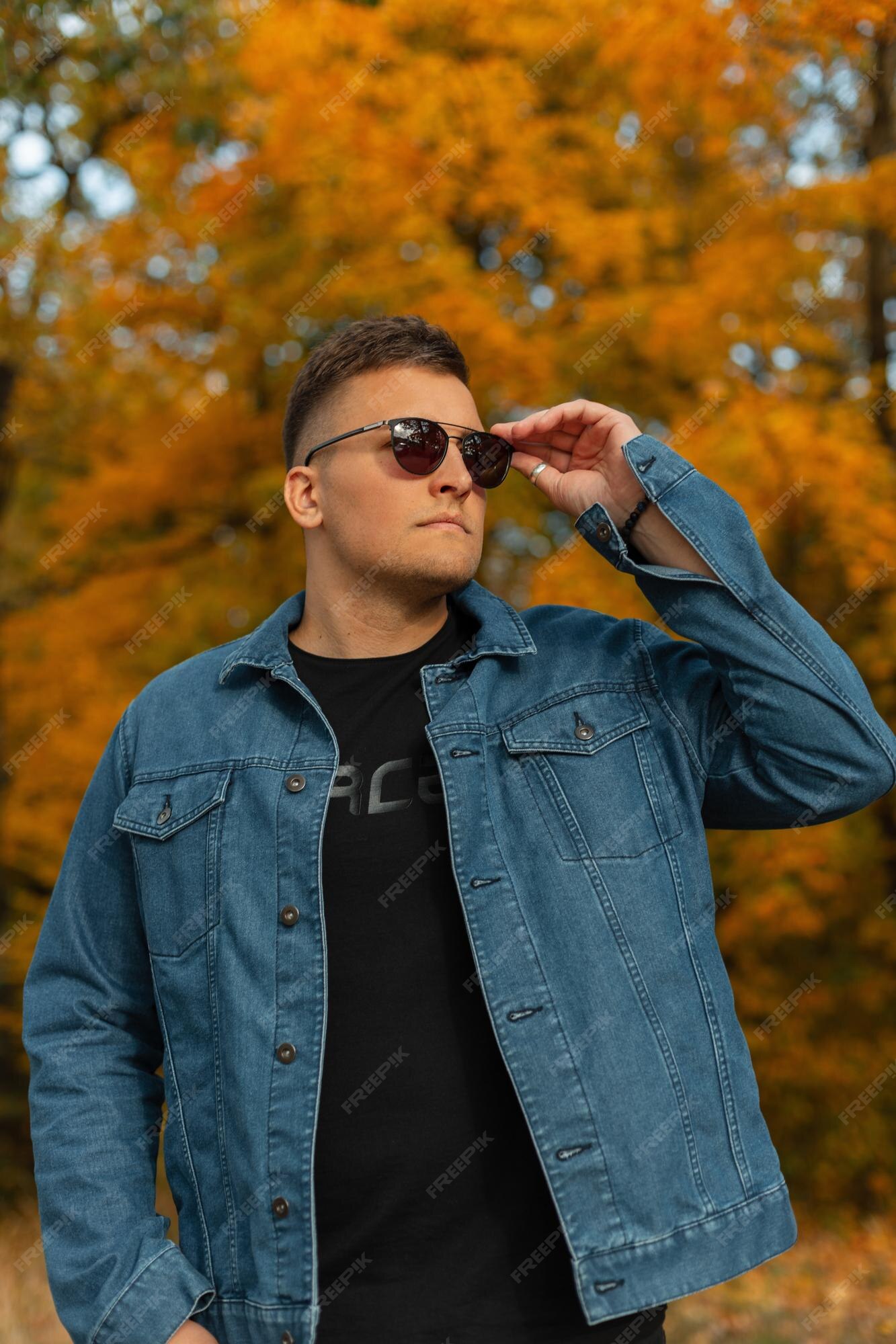 Modelo de hombre guapo moda en casual con chaqueta de azul y camiseta negra gafas de sol vintage frescas camina en un parque de otoño | Foto Premium