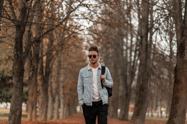 Modelo de hombre joven en una elegante chaqueta azul de mezclilla posando en el parque