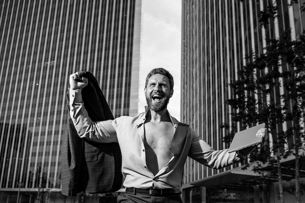 Modelo de hombre de negocios emocionado en camisa desabrochada al aire libre