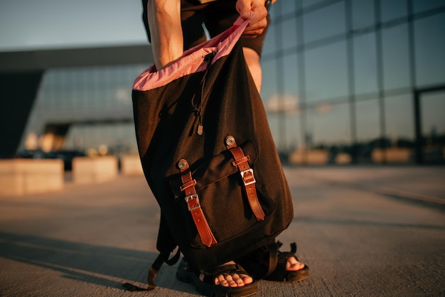 Foto modelo irreconhecível tira algo de uma mochila vestuário cinza em estilo minimalista moderno moda de rua para a primavera ou outono detalhes da aparência cotidiana