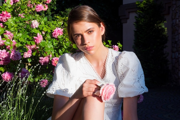 Modelo jovem de clima de primavera em vestido de verão no parque rosa de primavera linda jovem romântica com fluxo