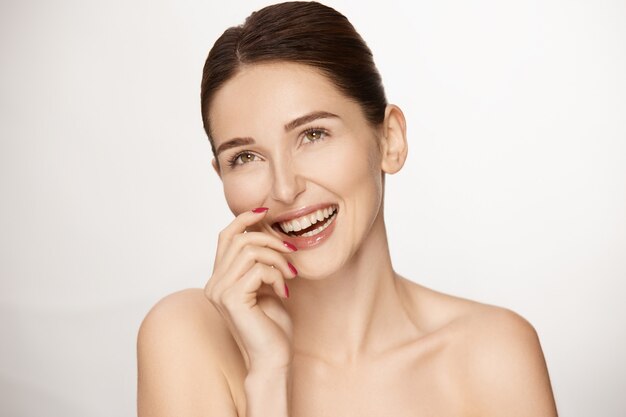 Modelo jovem feliz sorrindo e olhando para o topo, linda morena rindo isolada no fundo branco