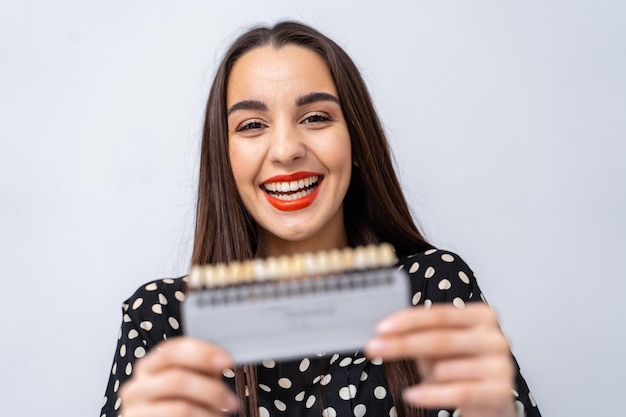 Modelo jovem segurando os dentes novos de plástico. linda fêmea com exemplos de dentes.