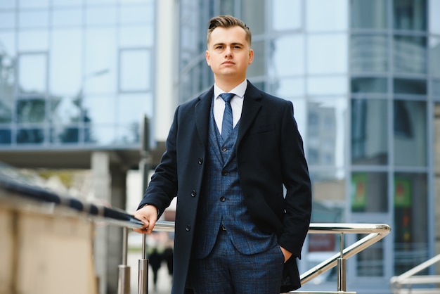 Modelo de joven empresario guapo seguro con estilo en traje de ropa caminando en la calle.