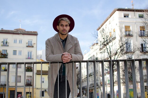 Modelo joven de moda con chaqueta gris y sombrero rojo en la calle