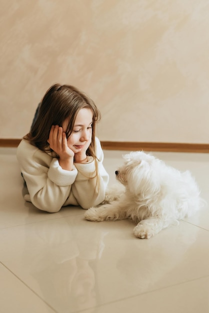 modelo juega con mascota perro blanco colegiala maltesa en casa estilo de vida en cocina beige