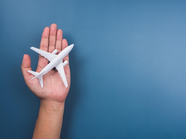 Modelo de juguete de avión blanco a mano sobre un fondo azul con espacio de copia, vista superior, estilo minimalista. Avión blanco, diseño plano. Vuelo, concepto de viaje.