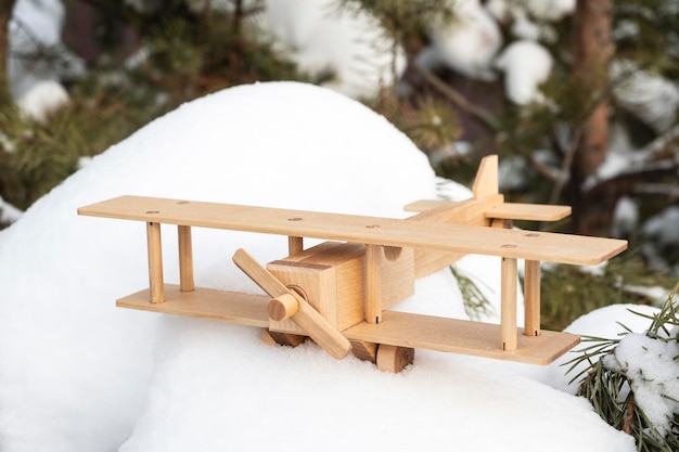 Un modelo de juguete de madera de un avión en la nieve contra el fondo de un bosque de invierno El concepto de turismo de viajes Hermoso fondo de invierno o postal Sueño de un viaje