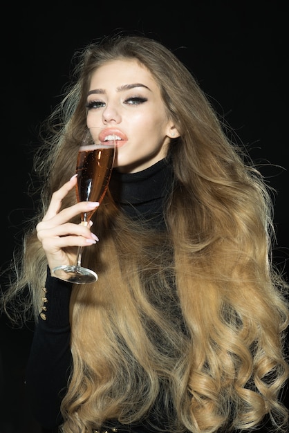 Modelo loira romântica sensual em roupas pretas com cabelo longo e saudável desfrutando de champanhe apaixonado