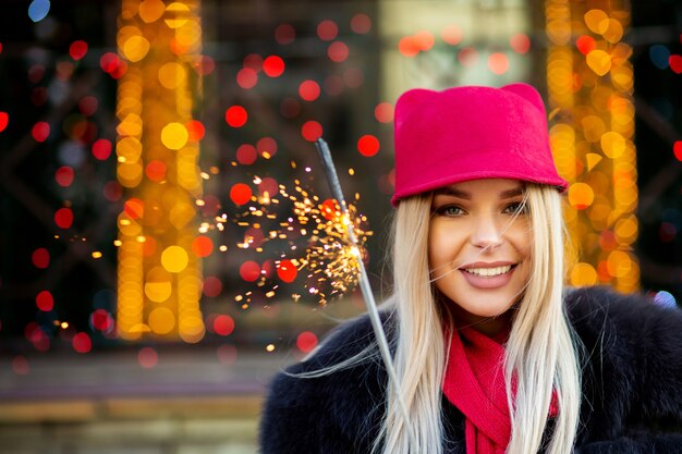 Modelo loira sorridente comemorando o Natal com estrelinhas no fundo de bokeh. Espaço para texto