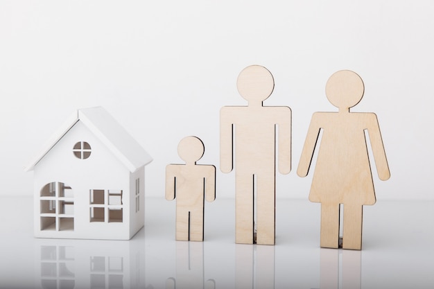 Modelo de madera de casa y familia aislado en primer plano blanco