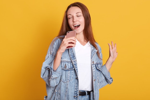 Modelo magnético emocional inspirado con cabello largo sosteniendo su teléfono inteligente en una mano