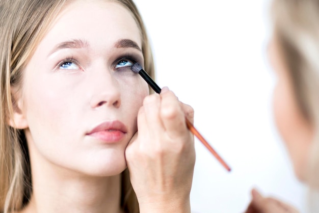 Modelo de maquillaje Artista de maquillaje pone sombra de ojos en chica