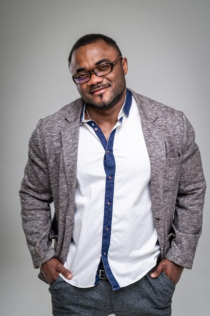 Modelo masculino afroamericano joven sonriente de aspecto natural aislado sobre fondo gris Hombre de moda en camisa blanca Primer plano