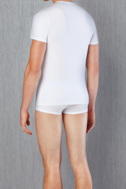 Modelo masculino con camiseta blanca y bragas frente a un fondo gris. Ropa interior masculina.