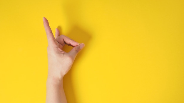 El modelo masculino está haciendo el signo de la mano "cuernos del diablo" en blackground amarillo.