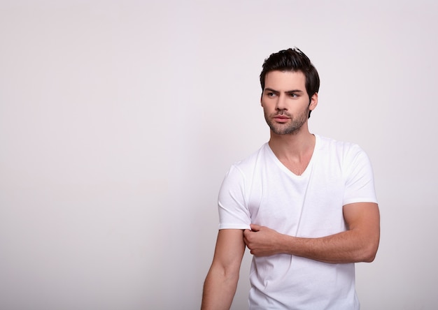 Un modelo masculino guapo en el estudio sobre un blanco se ve a un lado.