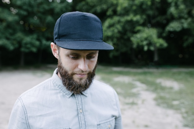 Modelo masculino guapo hipster con barba con gorra de béisbol en blanco negro con espacio para su logo