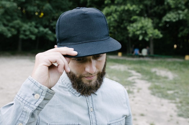 Modelo masculino guapo hipster con barba con gorra de béisbol en blanco negro con espacio para su logo