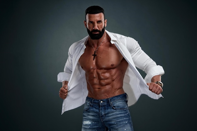 Modelo masculino musculoso vestindo camisa branca desabotoada expondo seu torso musculoso