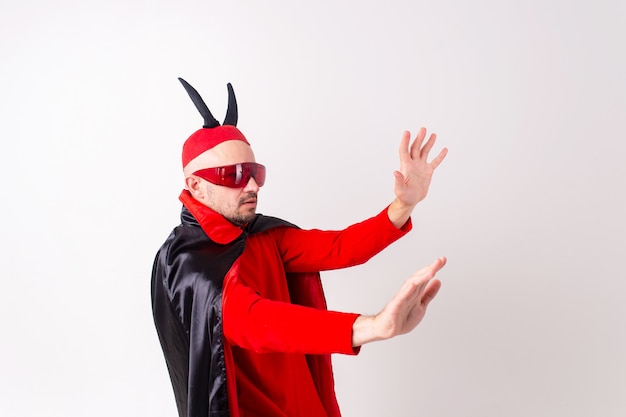 Modelo masculino en traje rojo negro de halloween y gafas de sol con sombrero y cuernos posando