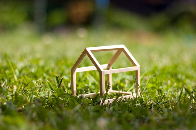 Modelo en miniatura de la casa de estructura de madera sobre fondo de hierba verde