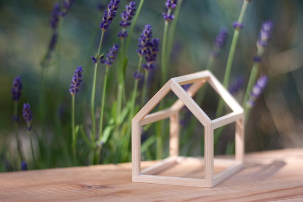 Modelo en miniatura de una casa con estructura de madera sobre una mesa de madera con flores de lavanda