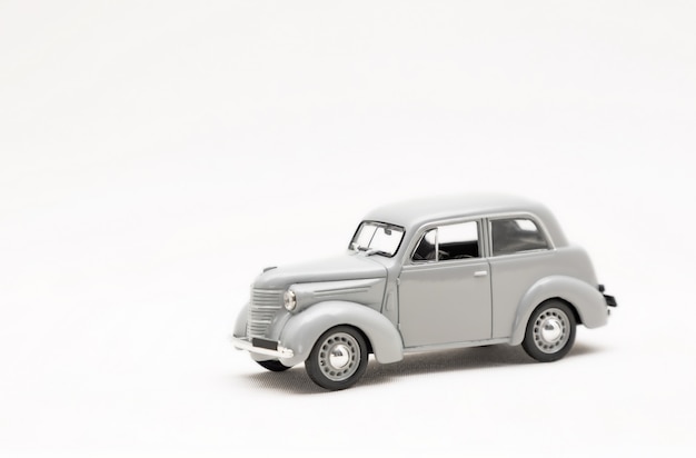 Modelo en miniatura de un coche retro gris de juguete sobre una superficie blanca