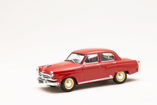 Modelo en miniatura de un coche retro rojo de juguete sobre una superficie blanca