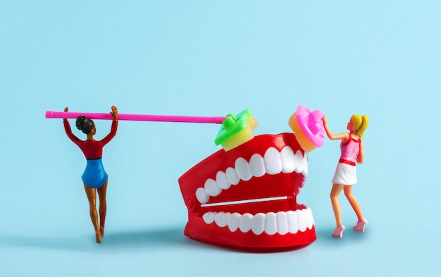 Foto modelo en miniatura de mujeres con cepillo modelo limpio de diente humano en fondo azul anuncio creativo