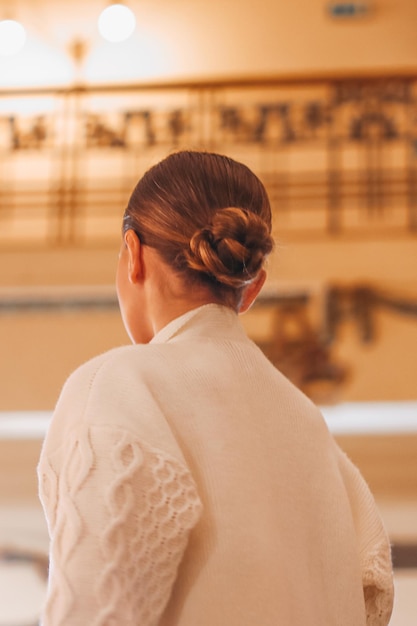 Modelo de moda en un cárdigan blanco de otoño y con un elegante peinado de moño Vista posterior