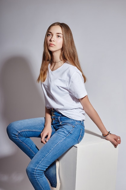 Modelo de moda joven hermosa en jeans azul blanco y camiseta blanca posando