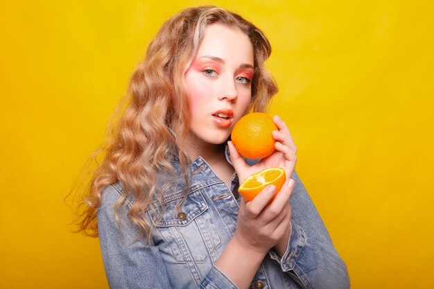 Modelo de moda joven hermosa con naranja en el rostro