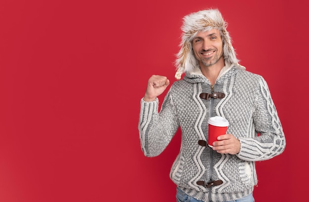 Modelo de moda masculina feliz sostenga la taza de café de la mañana de moda de invierno en una taza para llevar