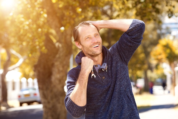 Modelo de moda masculino sonriendo afuera en otoño