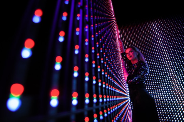 Modelo de moda mujer en coloridas luces de neón azules y púrpuras brillantes de neón, hermosa niña