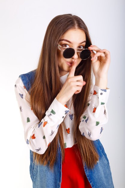 Modelo de moda mujer en gafas de sol, mini falda roja posando en blanco