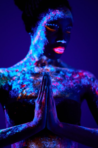 Modelo de moda mujer en modelo de luz de neón con maquillaje fluorescente en posición de oración diseño de arte de fem...