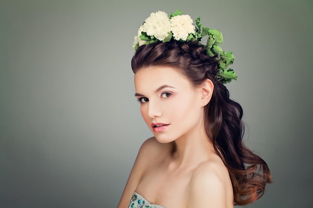 Modelo de moda con peinado de graduación y corona de flores de primavera en el fondo de la bandera. Mujer joven