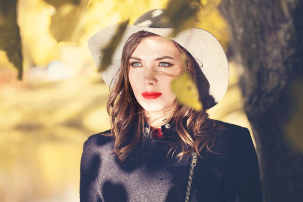 Modelo de moda perfecta mujer vestida con sombrero gris al aire libre, otoño soleado