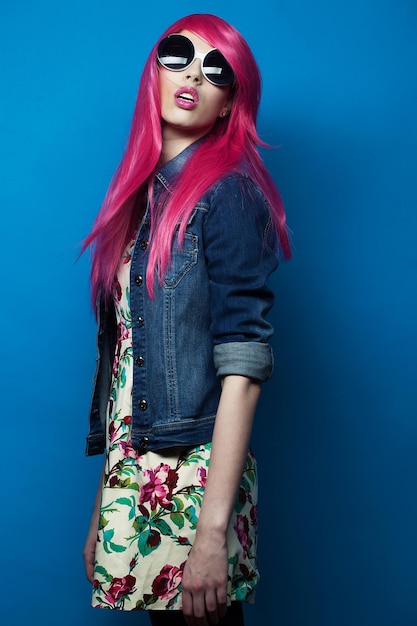 Modelo de moda de personas y concepto de moda con cabello rosado y grandes gafas de sol sobre fondo azul