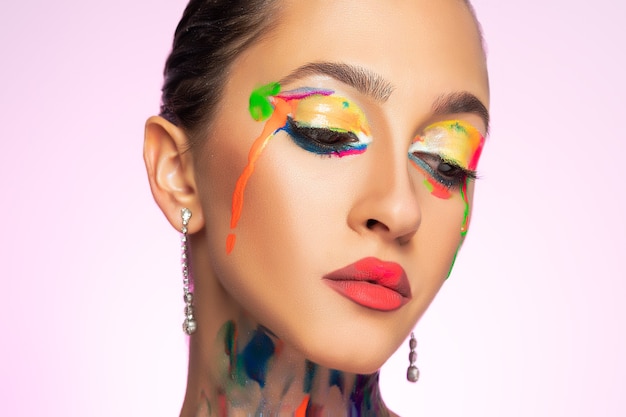 Foto modelo de moda con pintura colorida en su rostro.