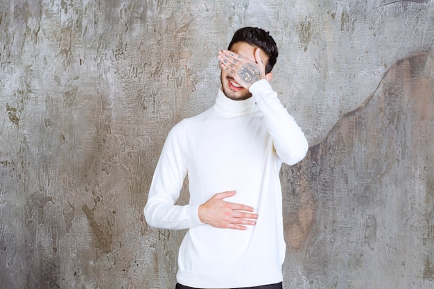 Modelo de moda en suéter blanco de pie sobre un muro de hormigón y parece somnoliento o cansado.