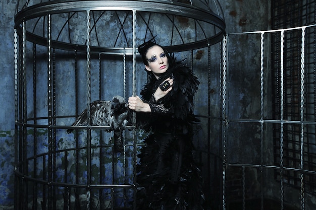 Modelo de moda en traje de fantasía posando en jaula de acero.