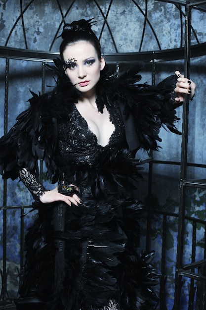 Modelo de moda en vestido de fantasía posando en jaula de acero.