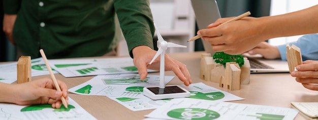 Modelo de molino de viento colocado en la mesa de reuniones de negocios verdes delineamiento de la vista frontal