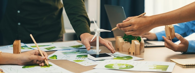 Foto el modelo de molino de viento representaba la energía renovable y el bloque de madera representaba la ciudad ecológica. se colocó en una mesa de reuniones de negocios verdes con documentos ambientales dispersos alrededor.