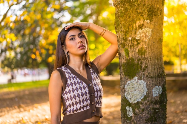 Modelo morena en otoño al atardecer en un parque natural de la ciudad con el sol de fondo