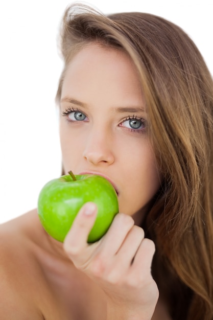 Modelo morena seria comiendo una manzana