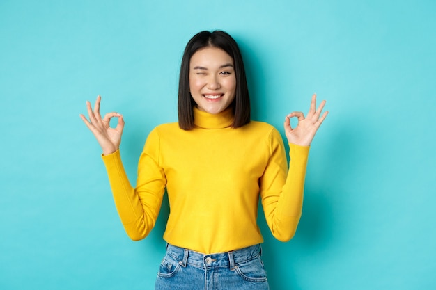 Modelo de mujer asiática alegre que muestra gestos bien, sonriendo y mirando impresionado, producto de alabanza